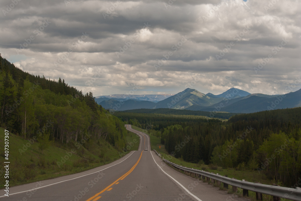Fototapeta premium Curving highway following the edge of the Eastern slopes of the Rocky Mountains of Alberta on a moody day