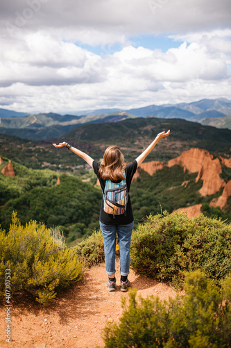 Cheerful woman with colorful backpack happily in the mountains
