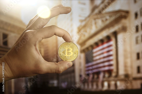 Bitcoin coin being held up outside the New York City Stock exchange building. Digital currency. Digital money. 