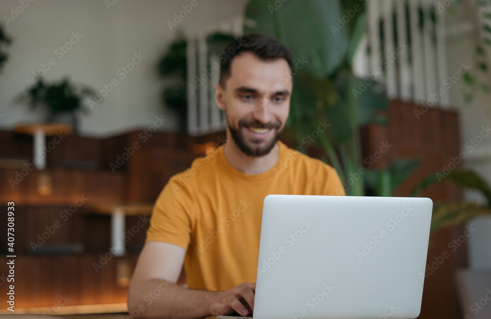 Handsome man freelancer working online, typing, searching information. Copy space. Blurred image of businessman using laptop computer, watching training courses, focus on laptop Handsome man freelancer working online, typing, searching information. Copy space. Blurred image of businessman using laptop computer, watching training courses, focus on laptop