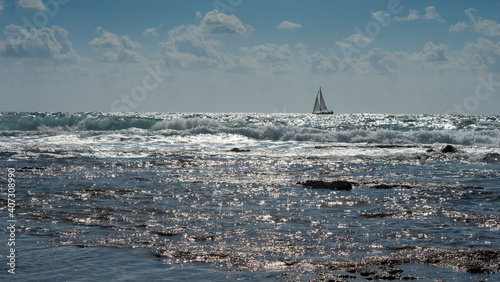 Sea worries, blue sky with clouds and a yacht on the horizon in the sunlight.