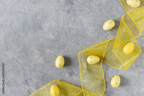 Yellow Easter eggs with yellow ribbon on grey background top view.