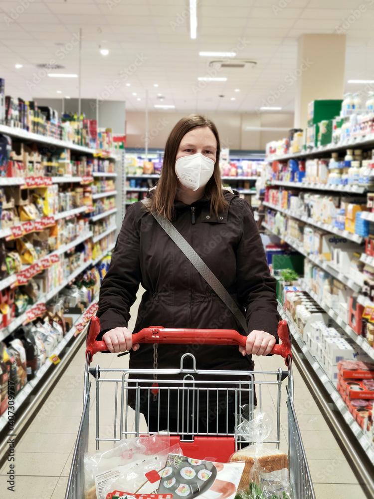 Frau mit FFP2 Maske wegen verschärfter Corona Maskenpflicht im Einzelhandel steht im Supermarkt Discounter um die Covid-19 Pandemie zu bekämpfen