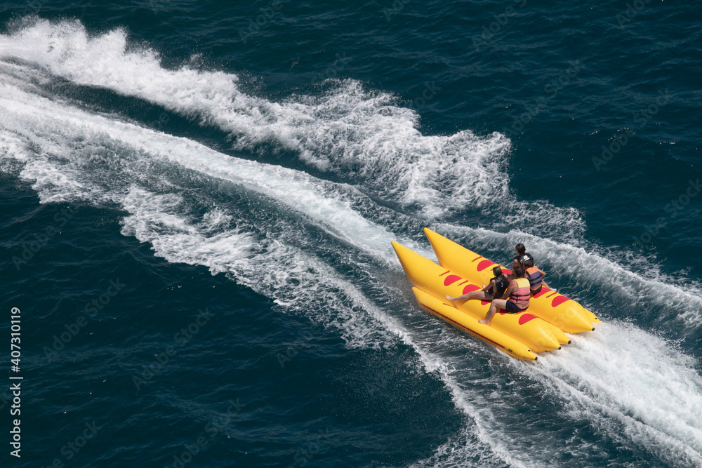 People are riding yellow inflatable boat on the sea.