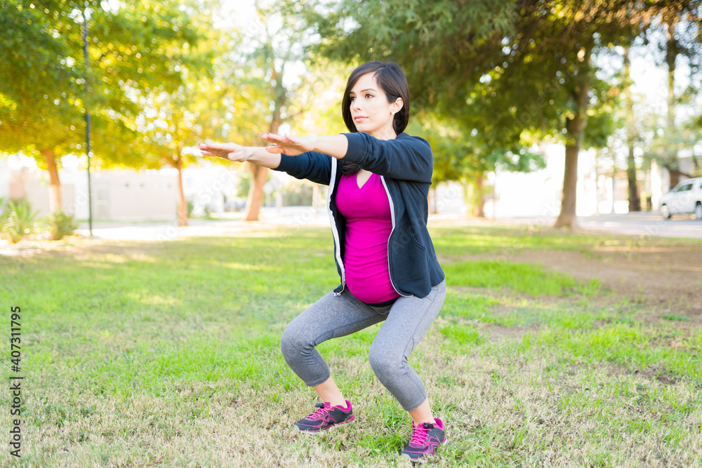 Fit and sporty pregnant woman squatting outdoors