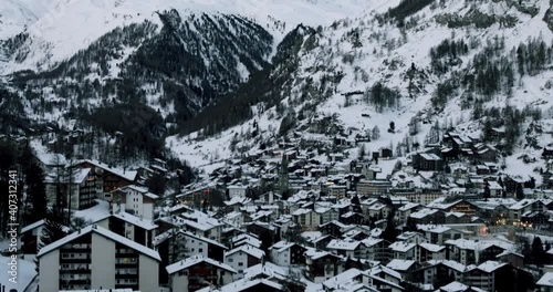 Cityscape of the Swiss village of Zermatt in Valais in winter, at dawn with snow and illuminations. The Matterhorn and the Alpine mountain range in the background.