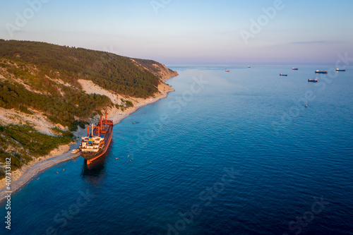 Fototapeta Naklejka Na Ścianę i Meble -  Big cargo ship running aground. view from above. Panorama of the sea bay at sunset