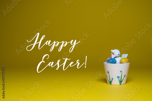 Happy Easter greeting card background with text message.  Cute little chick with colorful easter egs on yellow background.