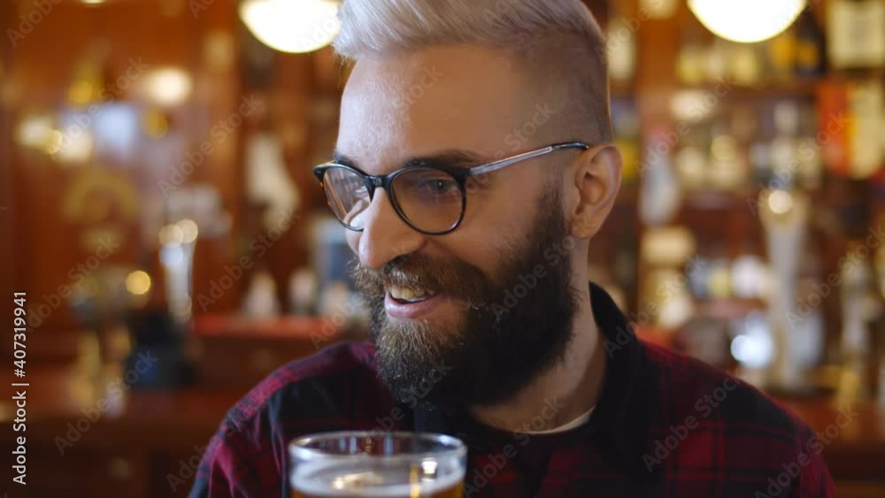 Close up of bearded hipster guy in glasses talking to friends in bar