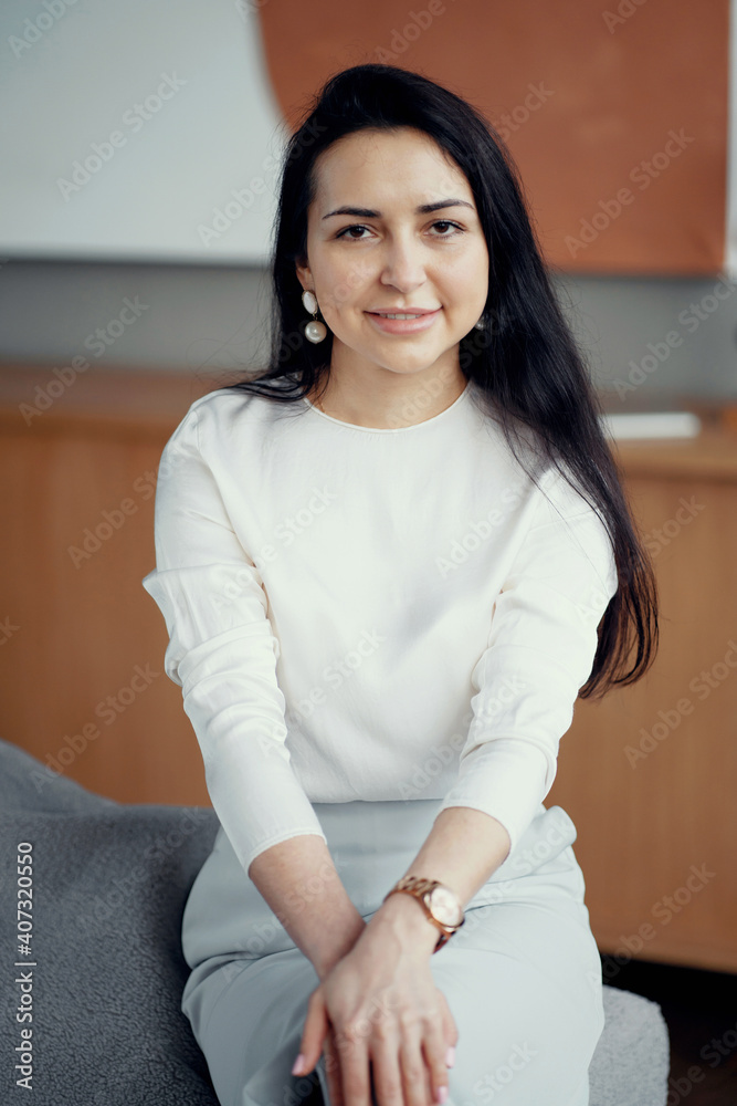 confident young brunette woman smiling sitting on a chair in the office. Dressed in business clothes and shoes, waiting for her work partner. confident young brunette woman smiling sitting on a chair in the office. Dressed in business clothes and shoes, waiting for her work partner.