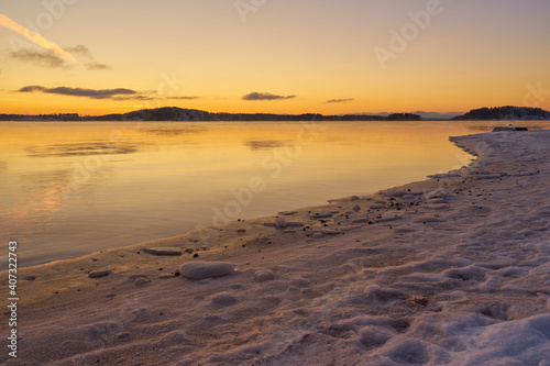 The coast of the sea in ice and in the snow at sunset.