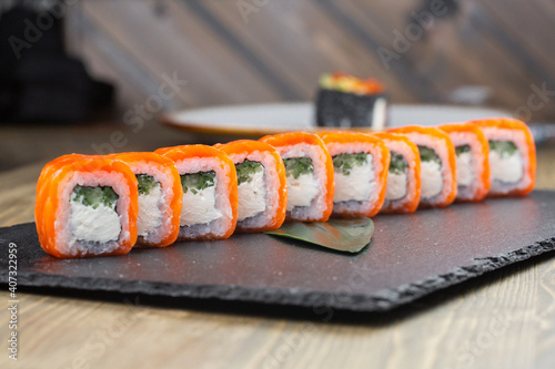 Close-up of uramaki sushi rolls with red caviar, salmon, tuna, cucumber and avocado isolated on black background. Delicious traditional japanese food with sushi rolls.