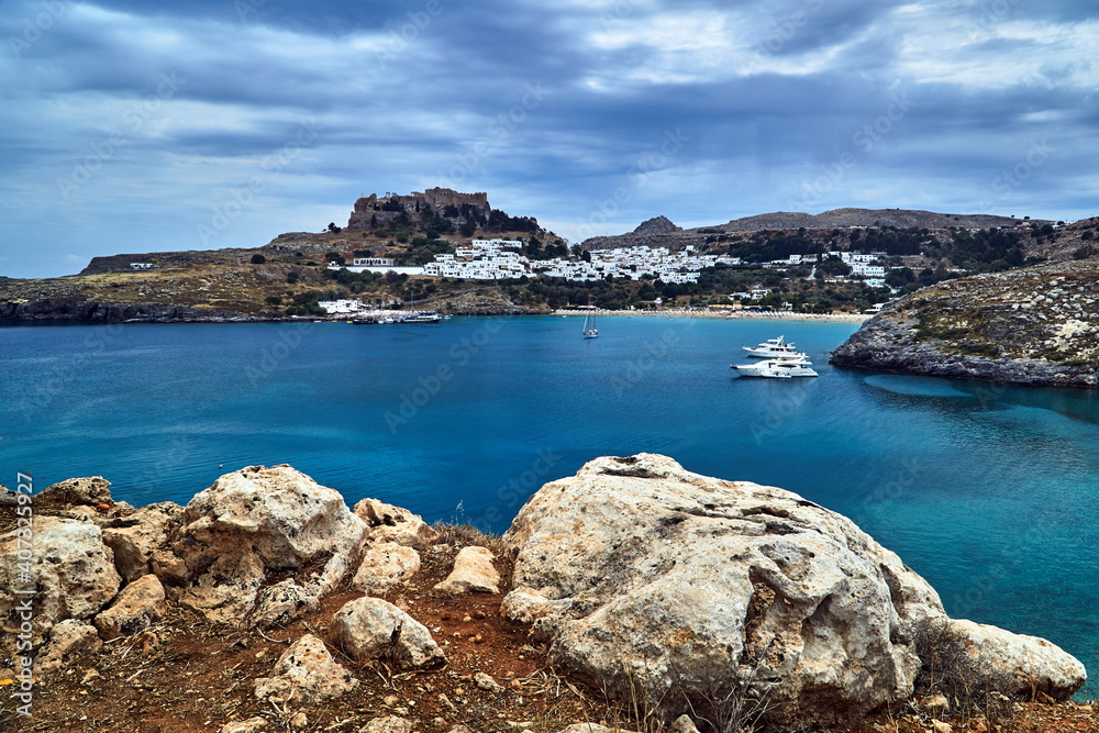 a bay with a rocky coast, the town of Lindos and a medieval fortress