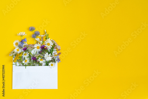 Fototapeta Naklejka Na Ścianę i Meble -  bouquet of flowers in envelope with yyellow background.top view.copy space