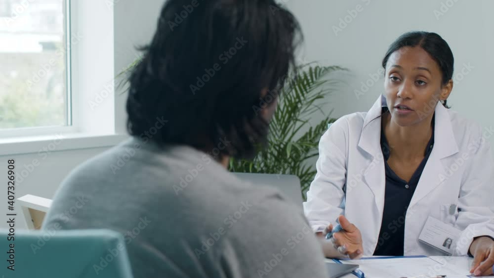 Young Doctor Using Clipboard and Talking to Patient