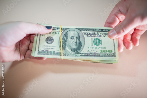 Фотография Close-up of one hand handing another hand a pile of US bills
