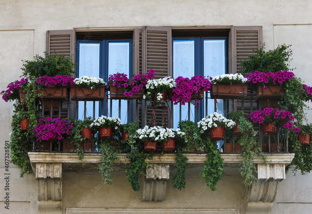 Fototapeta premium Windows among a decorated balcony of flowers