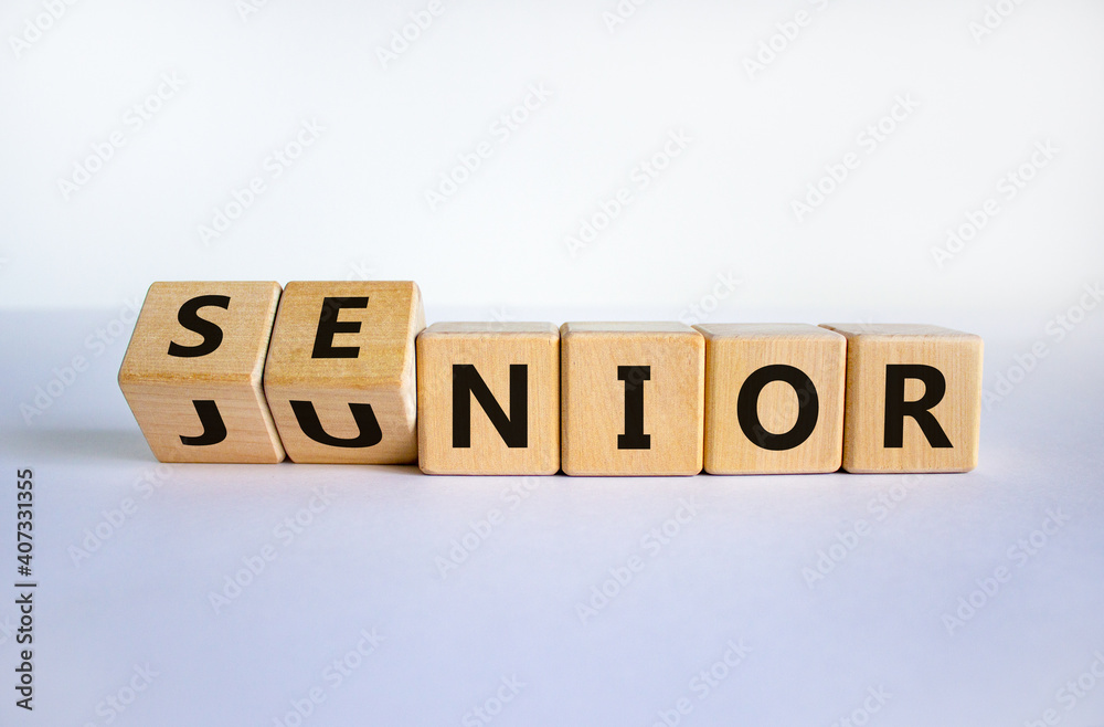 From junior to senior symbol. Turned cubes and changed the word 'junior' to 'senior'. Beautiful white background, copy space. Business and junior or senior concept. - obrazy, fototapety, plakaty 
