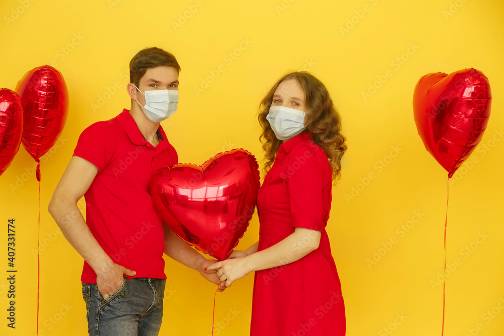 Medicine flu virus ill sick disease treatment concept. Young Happy couple in protective face mask hold heart-shaped balloon on yellow backgroun. Valentines day. Pandemic and feelings concept Medicine flu virus ill sick disease treatment concept. Young Happy couple in protective face mask hold heart-shaped balloon on yellow backgroun. Valentines day. Pandemic and feelings concept