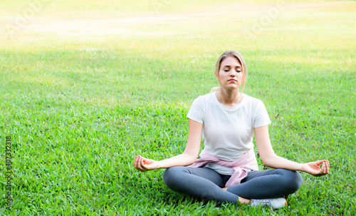 Woman sitting in lotus position closed eyes do meditation breathing technique outdoors, keep calm, healthy life habits and lifestyle concept. Beautiful sporty practicing yoga doing lotus pose. © ravipat