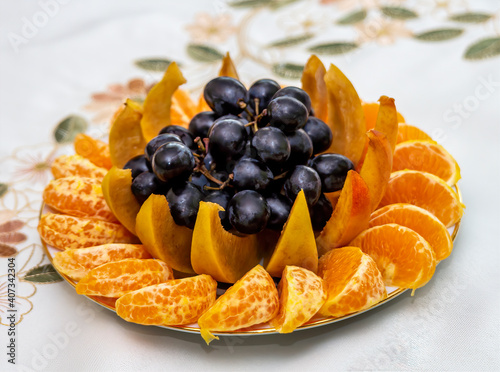 A plate of fruit. it contains juicy grapes  bright tangerine and fragrant peach