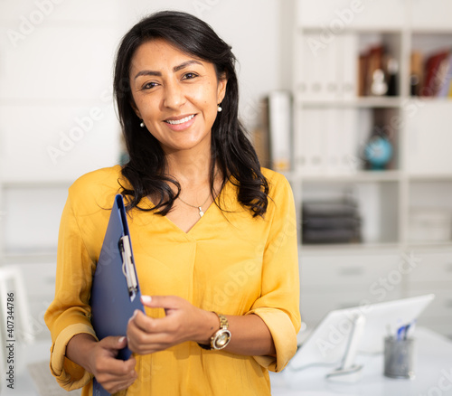 Cheerful business woman in light office holding clipboard with papers document write notes photo