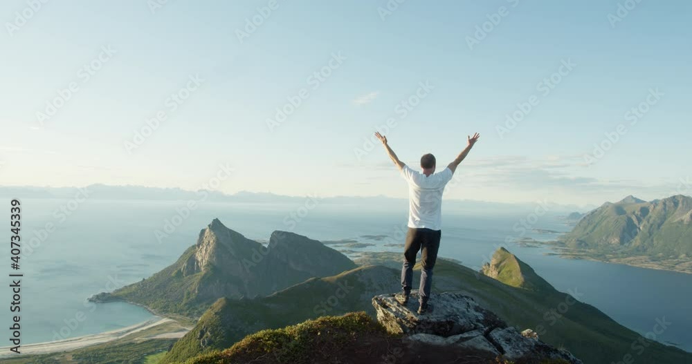 Norwegian raising arms in sunset celebrating climbing mountain - static rear shot Norwegian raising arms in sunset celebrating climbing mountain - static rear shot