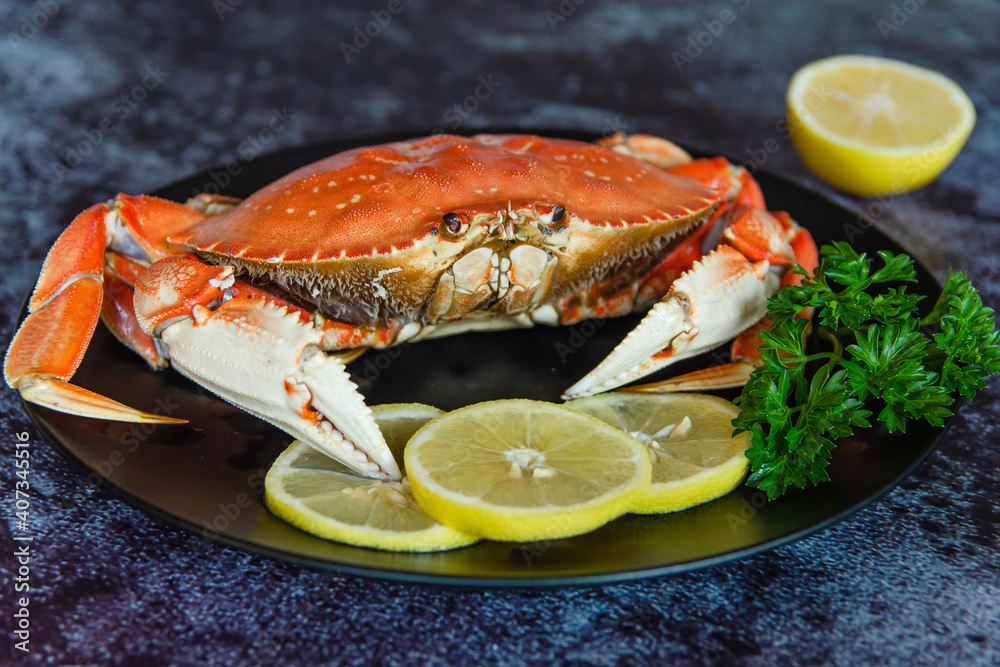 One boiled crab with lemon and parsley on a black plate. One boiled crab with lemon and parsley on a black plate.