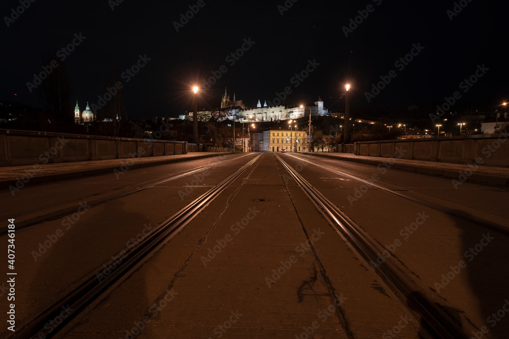 .tracks for the tram on the road and in the background Prague Castle in the center of Prague and light from the street lights