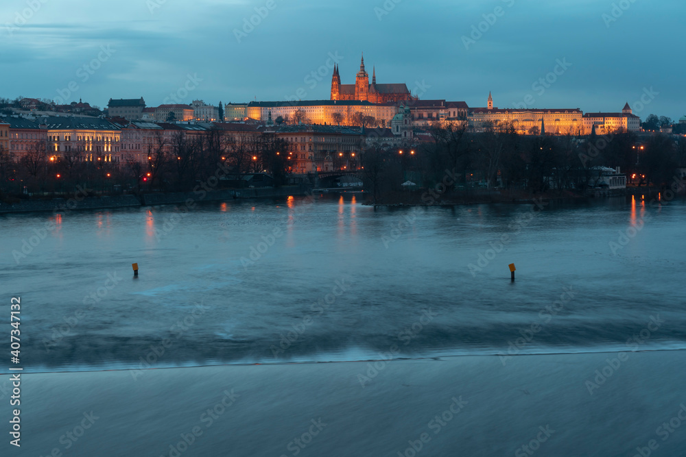 .view of the Vltava river and in the background the Prague castle and the Church of St. Vitus in the center of Prague in the early evening and the lights of the street lights