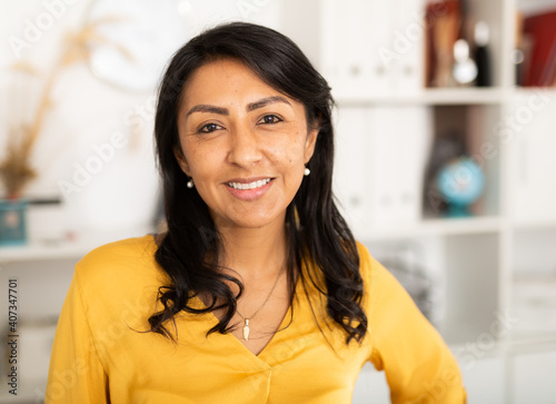 Happy smiling Latin American businesswoman standing in office and looking at camera photo