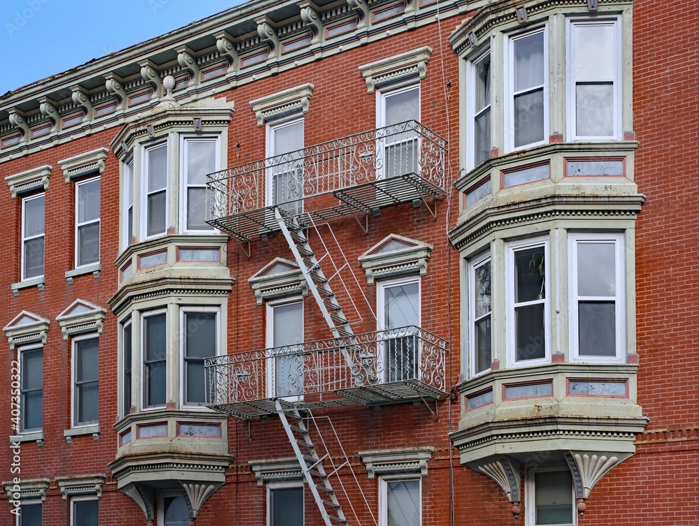 Old apartment building with ornate roof line cornice and exterior fire escape ladder