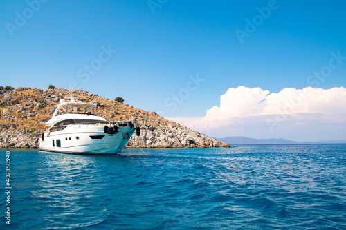 Fototapeta A white luxury yachting boat anchored in a turquoise color wonderful sea bay