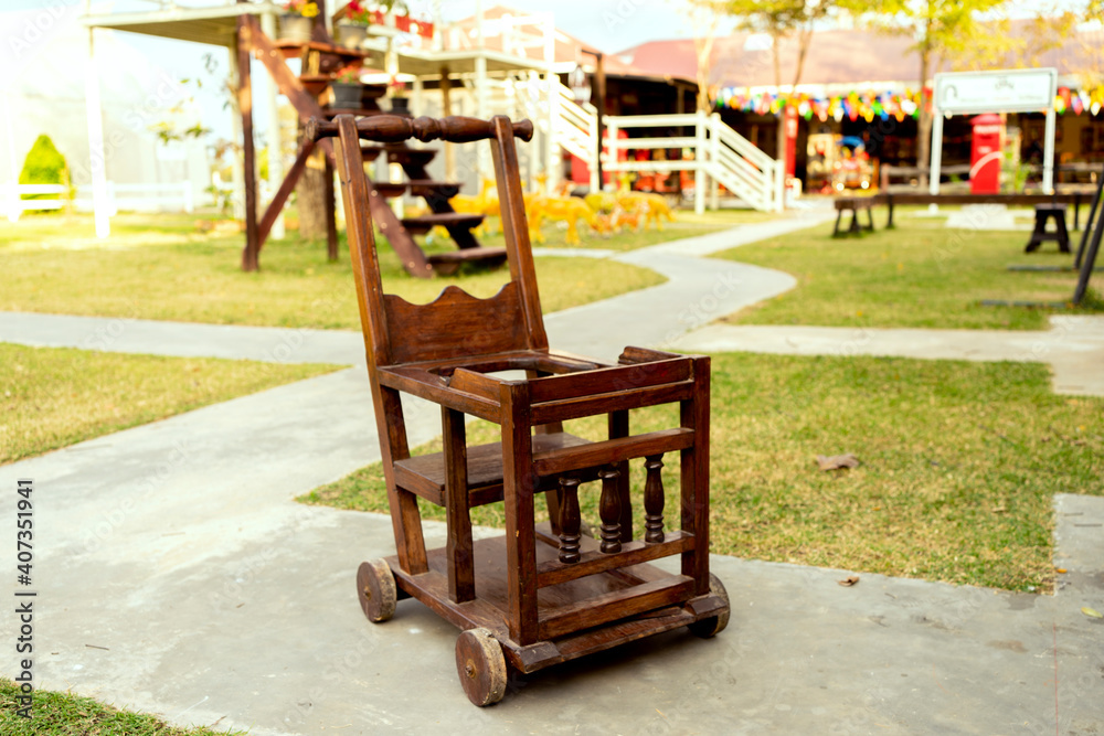 Fototapeta premium The ancient wooden stroller made of wood with wheels and a place to put toys in front for the child.
