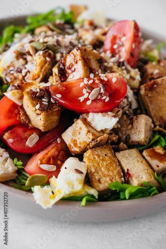 recipe for a healthy diet salad of tofu cheese, tomatoes, eggs, dressing, sesame seeds and seeds. vertical vegetarian food content, close-up, selective focus