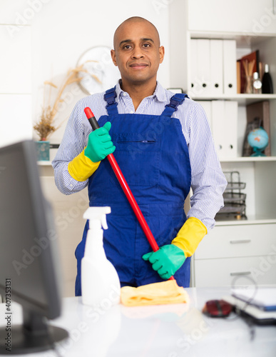 Fotografía Professional cleaner standing in office with broom and cleansers