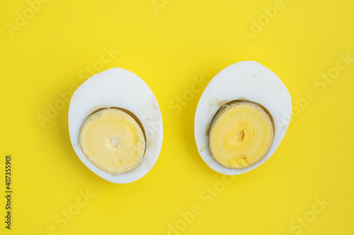 Halves of a boiled egg, a hard boiled egg cut in half on a yellow background, top view.
