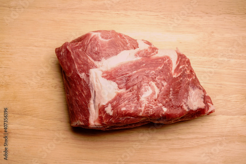 A piece of pork on a wooden chopping board. Layers of white fat are visible. Fresh meat.