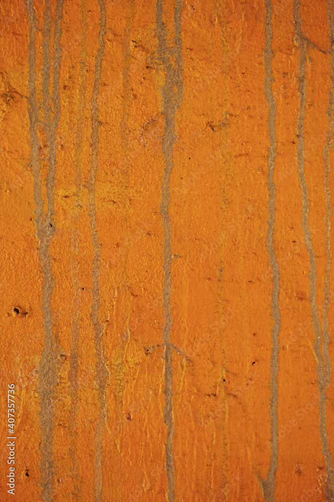 狐色のペイントに垂れた跡の線が付いている古いコンクリートの壁