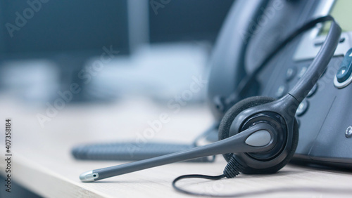 close up on headset with telephone devices at office desk for customer service support concept