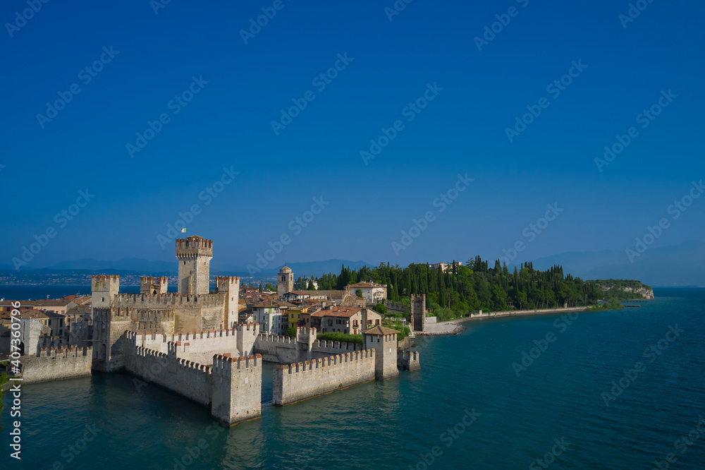 Amazing view to the old bridge and harbor of Sirmione. Aerial view on Sirmione sul Garda. Italy, Lombardy. View by Drone. Rocca Scaligera Castle in Sirmione.