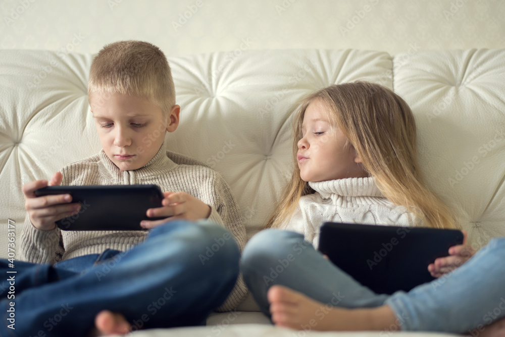 Two little children boy and girl holding tablet and watching cartoons at home, having fun with digital device. Two little children boy and girl holding tablet and watching cartoons at home, having fun with digital device.