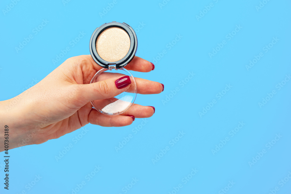Female palm holding pack of eyeshadows against blue background Female palm holding pack of eyeshadows against blue background