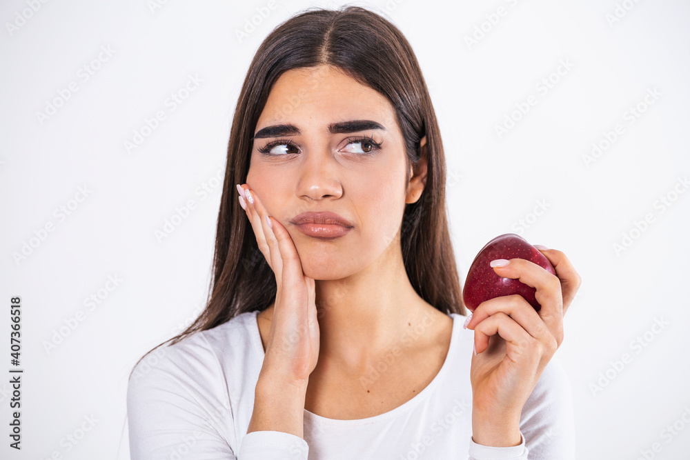 Sensitive Teeth. Young Woman Having Tooth Pain Eating Apple Standing On Gray Studio Background. woman who feels toothpain because of sensitive teeth Sensitive Teeth. Young Woman Having Tooth Pain Eating Apple Standing On Gray Studio Background. woman who feels toothpain because of sensitive teeth