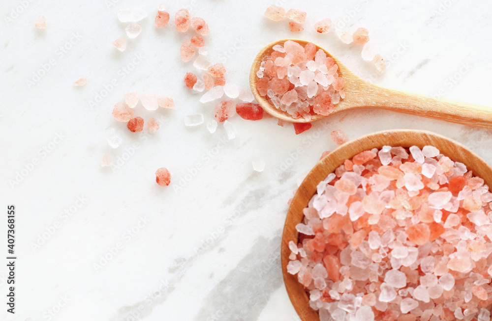 top view of himalayan pink rock salt in wooden bowl and spoon on white marble table. - obrazy, fototapety, plakaty 