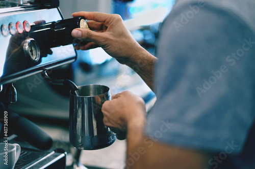 Barista is milk steaming on espresso coffe machine  frother latte art in coffee mug at Coffee shop.