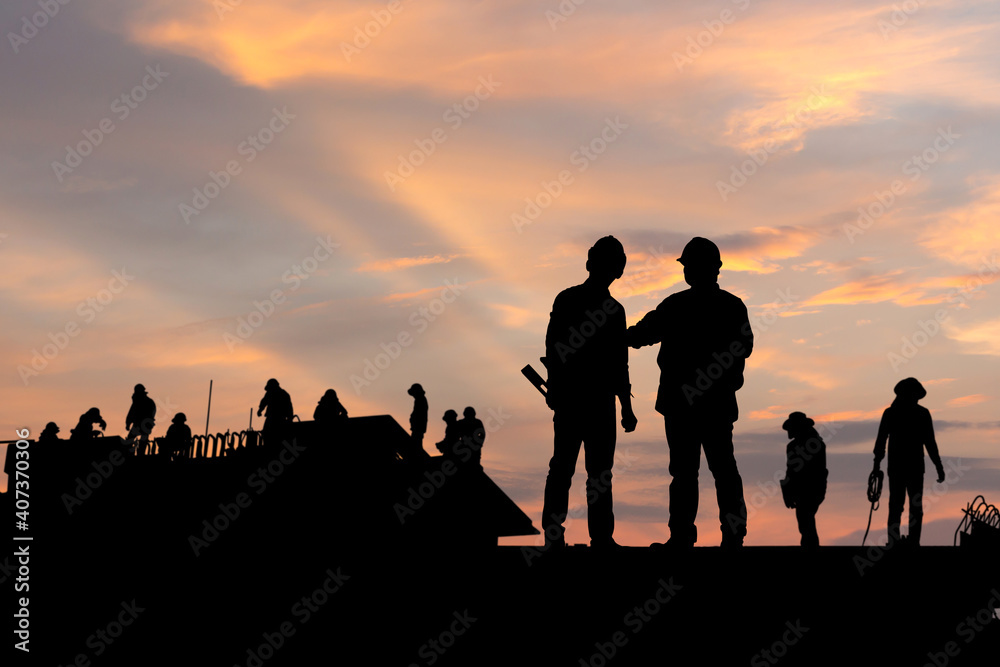 Silhouette of Engineer and worker on building site, construction site at sunset in evening time Silhouette of Engineer and worker on building site, construction site at sunset in evening time