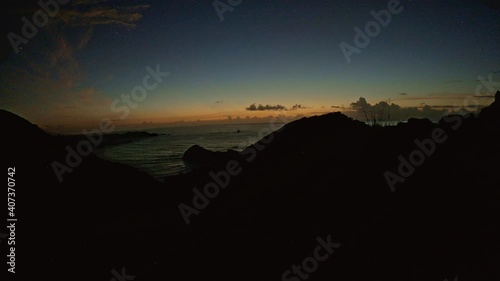 Timelapse Of Sunset Setting Over Ocean With People Walking On Coastal Cliffs. - wide shot photo