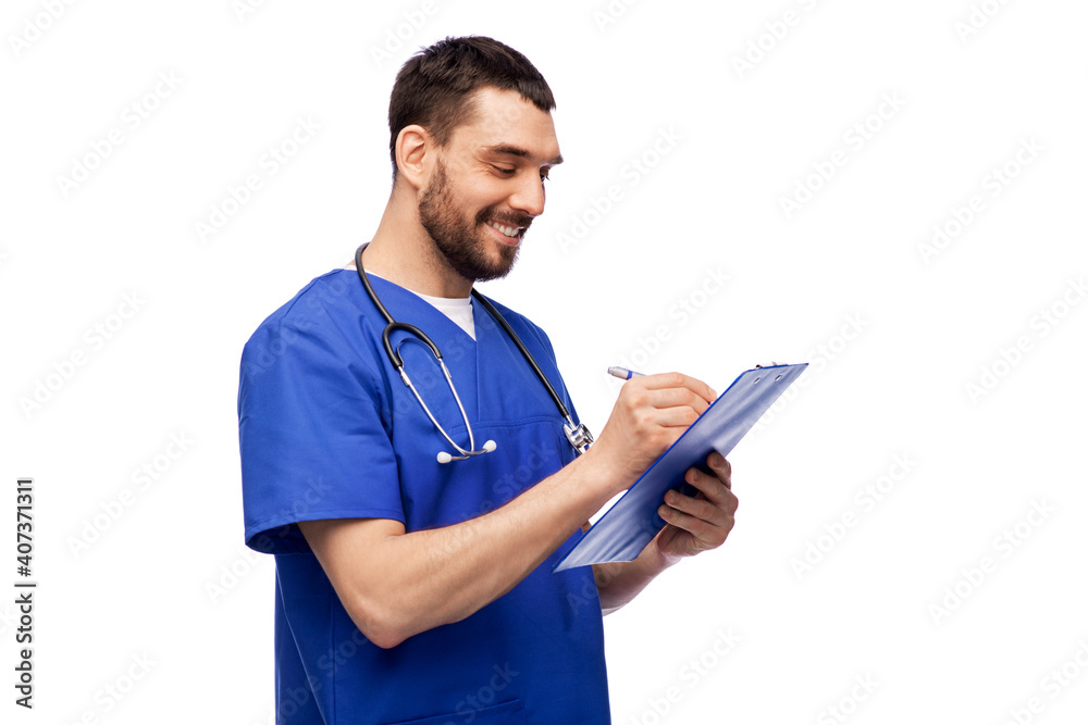 healthcare, profession and medicine concept - happy smiling doctor or male nurse in blue uniform writing medical report on clipboard over white background
