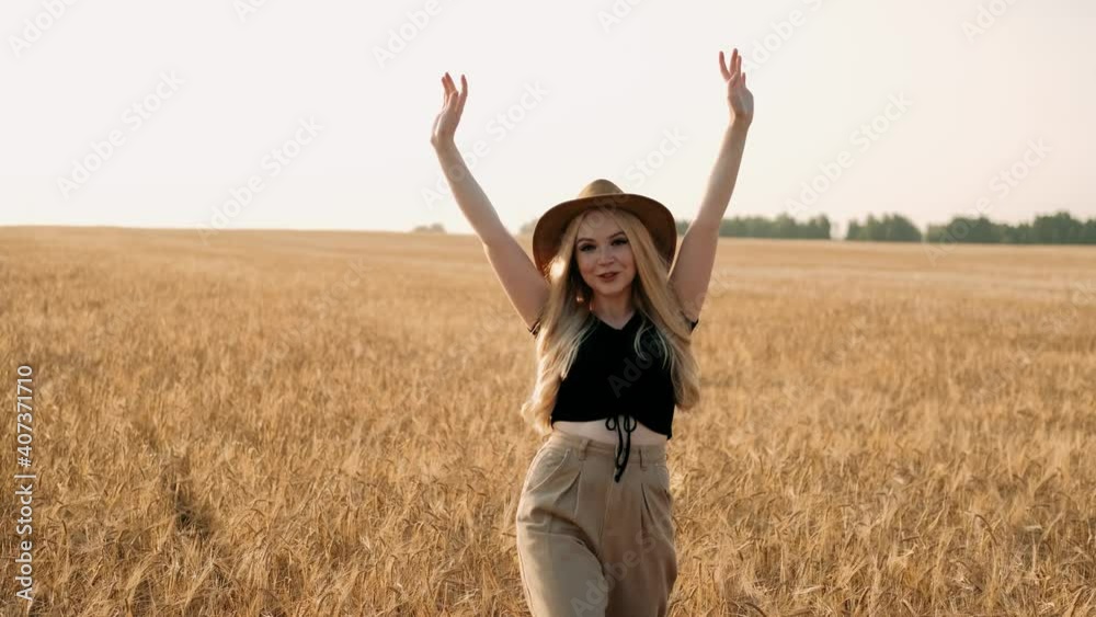 Girl in hat and hat walking on wheat field in summer and touching ripe wheat ears. Blonde girl enjoying peacefulness and beautiful nature. Concept of harvest. Freedom concept. Girl in hat and hat walking on wheat field in summer and touching ripe wheat ears. Blonde girl enjoying peacefulness and beautiful nature. Concept of harvest. Freedom concept.